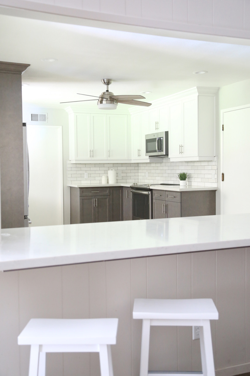 a closeup of a marble countertop island with a white tile splashback in the background