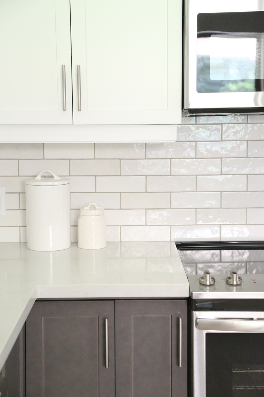 a closeup of white marble countertops and white tile splashback